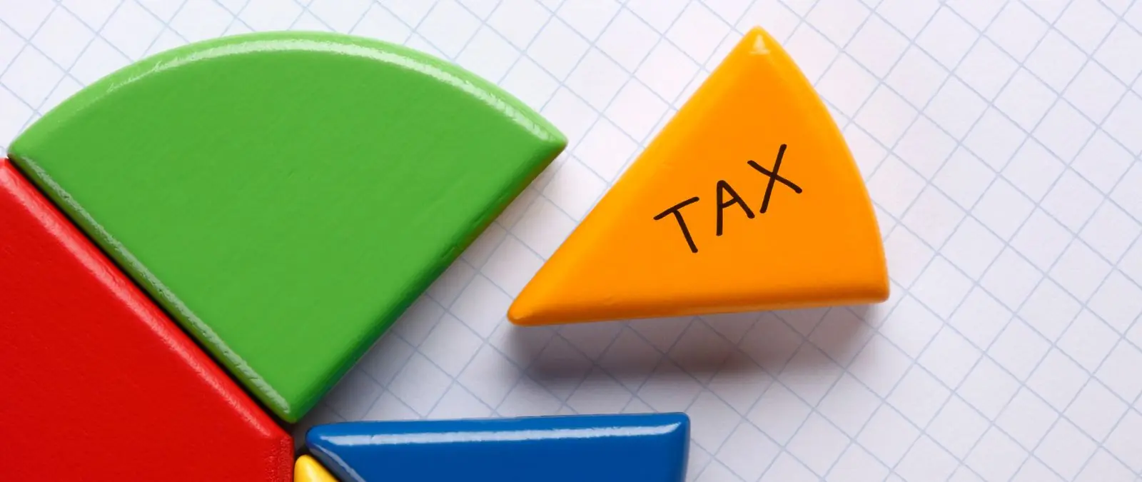 カラフルな円形の積み木の中にTAXと書かれたオレンジの積み木がある